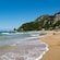 A sandy beach next to cliffs scattered with vegetation